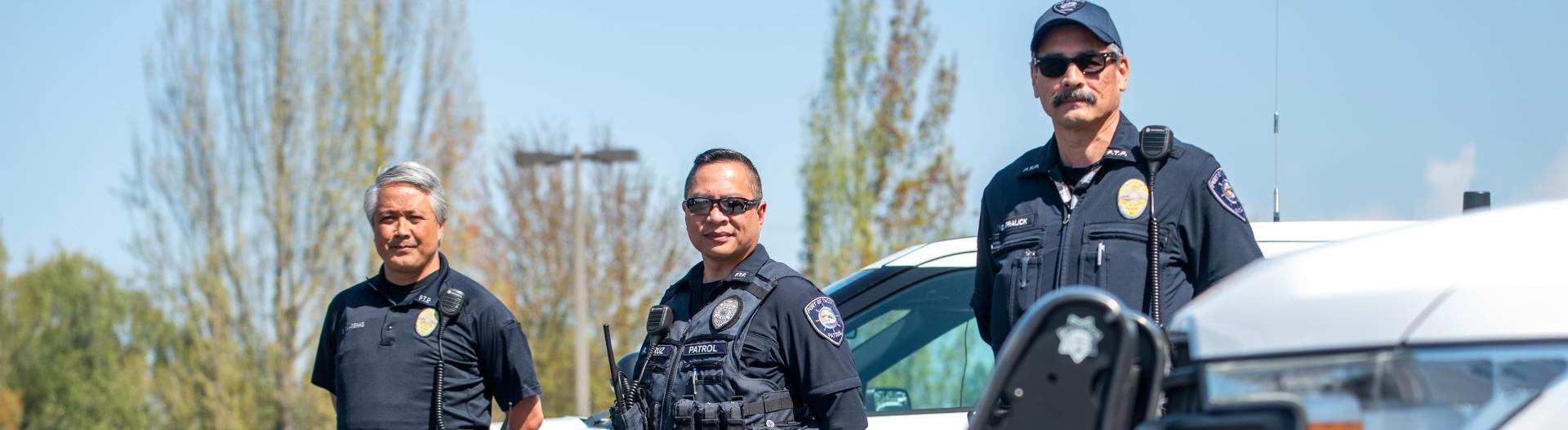 Photo of three security officers standing in front of their Port patrol cars.